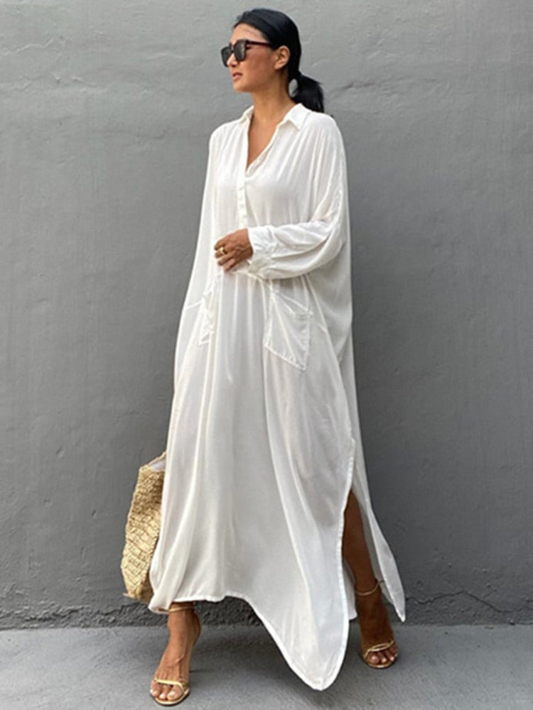 Woman wearing a white maxi beach dress kaftan as a swimsuit cover-up, perfect for summer beach and pool outings.