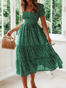 Woman in a vintage print maxi dress with puff sleeves and square collar, perfect for summer beach and casual outings.