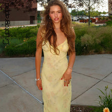Woman wearing a vibrant summer floral maxi dress with a plunging neckline and backless design, perfect for beach vacations.