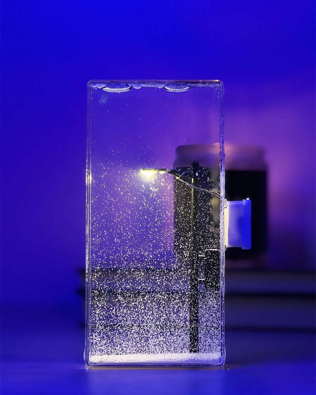 Warm LED snowfall night lamp glowing in a cozy winter bedroom

