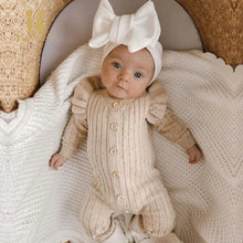 Woman wearing a stylish ruffle sleeve knitted jumpsuit in a cozy setting

