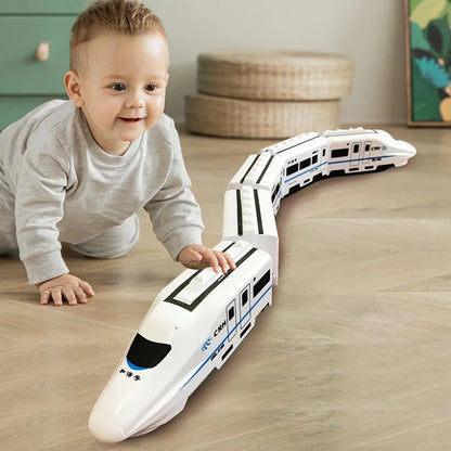 A young child playing with a white electric toy train set on a wooden floor.