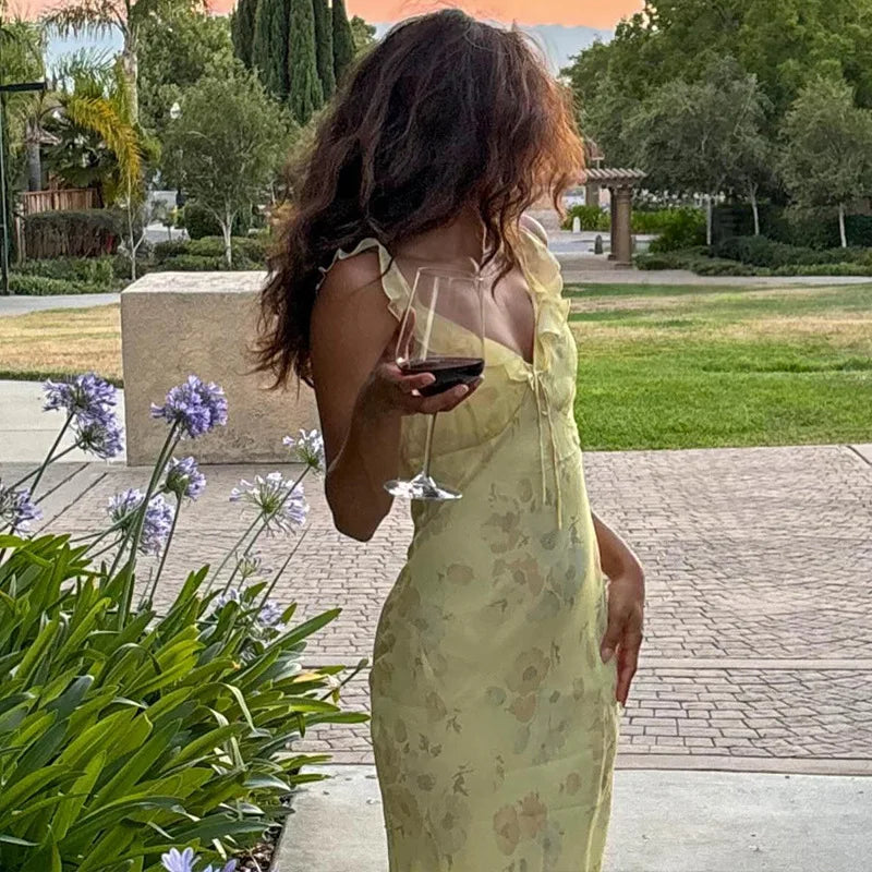 Woman wearing a vibrant summer floral maxi dress with a plunging neckline and backless design, perfect for beach vacations.