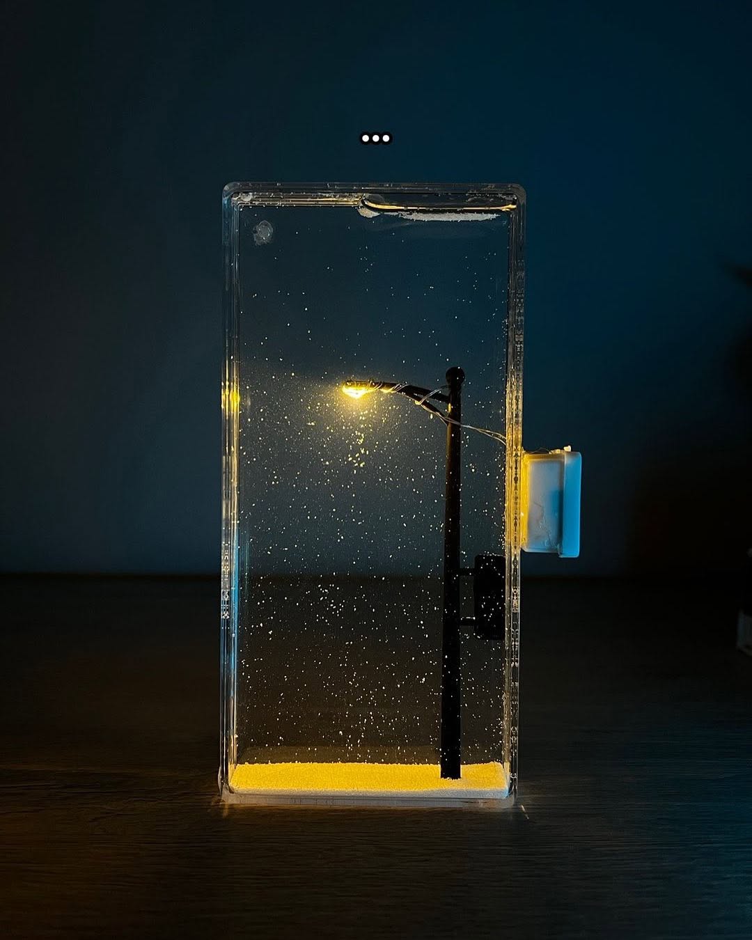 Warm LED snowfall night lamp glowing in a cozy winter bedroom

