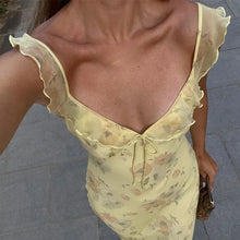Woman wearing a vibrant summer floral maxi dress with a plunging neckline and backless design, perfect for beach vacations.